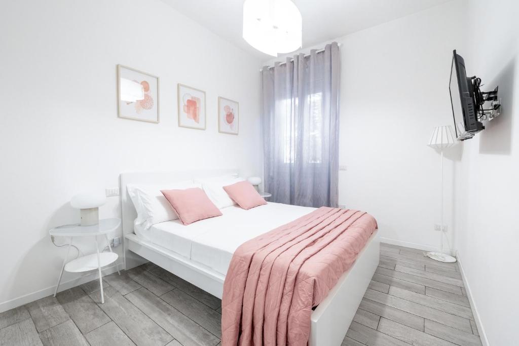 Dormitorio blanco con cama con manta rosa en Appartamento La Fortezza en Milán