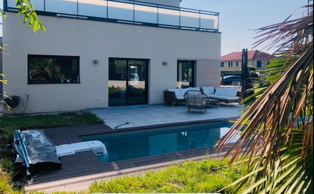 un patio trasero con piscina y una casa en Villa piscine 6 personnes en Meyzieu