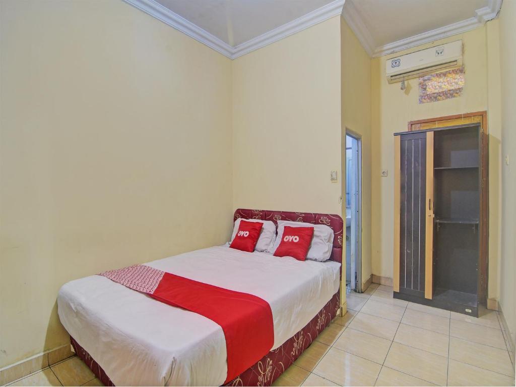 ein Schlafzimmer mit einem Bett mit roten Kissen darauf in der Unterkunft OYO 92964 Kost 99 in Manado