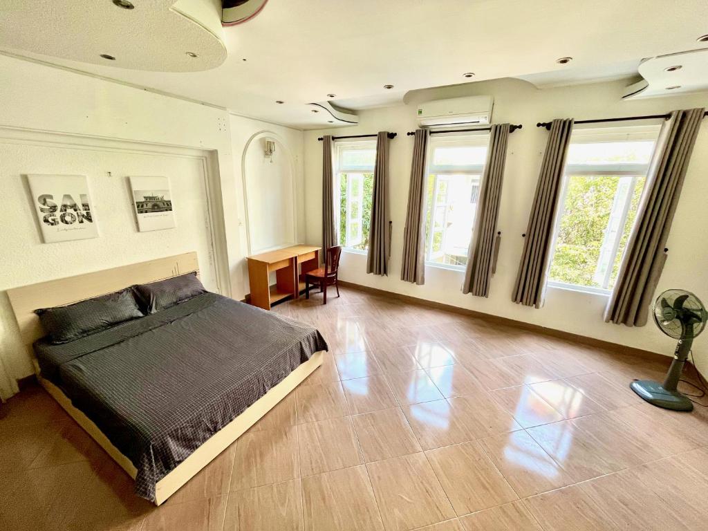 - une chambre avec un lit, un bureau et des fenêtres dans l'établissement Nguyen Shack - Sai Gon, à Hô-Chi-Minh-Ville