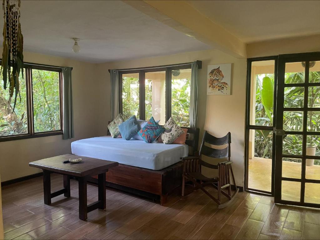 Casa Jaguar Tortuguero في تورتوجويرو: غرفة نوم بسرير وطاولة ونوافذ
