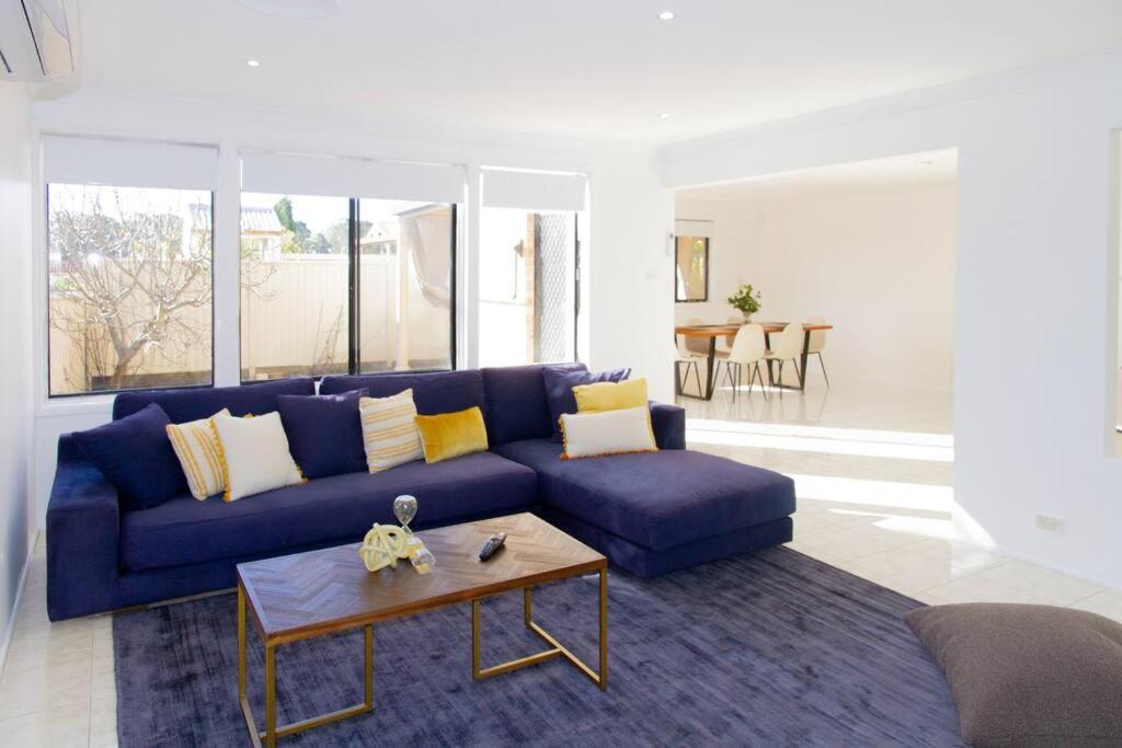 sala de estar con sofá azul y mesa en Sunny & Spacious Family Retreat, en Prestons