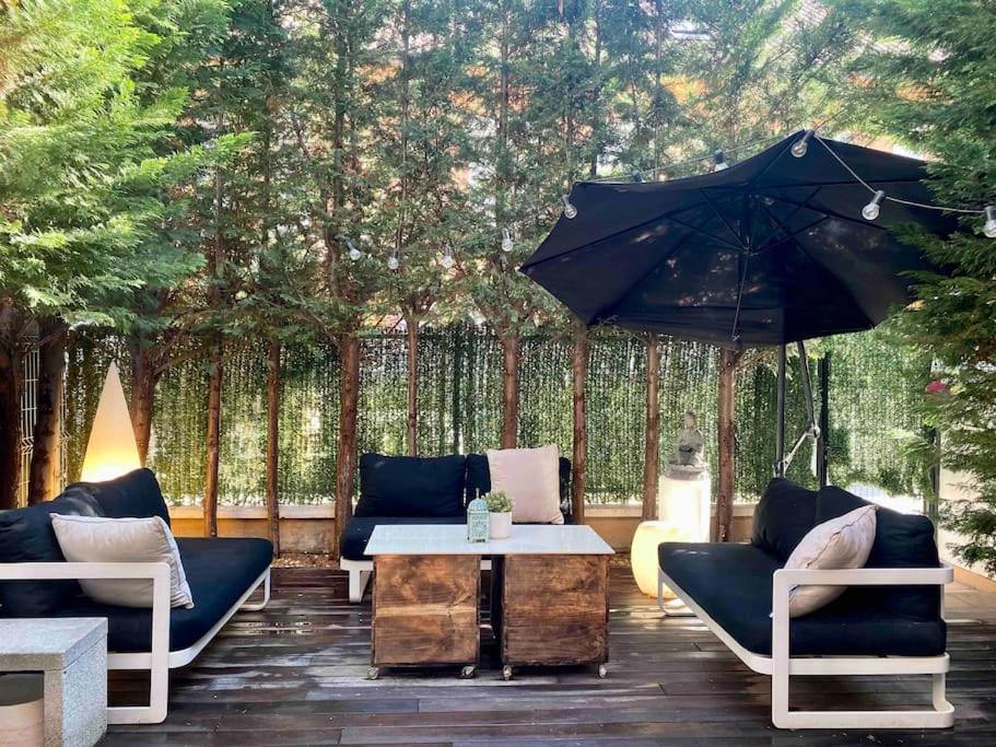 eine Terrasse mit Sofas, einem Tisch und einem Sonnenschirm in der Unterkunft Adosado residencial -4km centro in Logroño