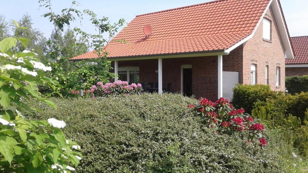 una casa con techo rojo y flores en Haus Seeblick Nr 48, en Geeste