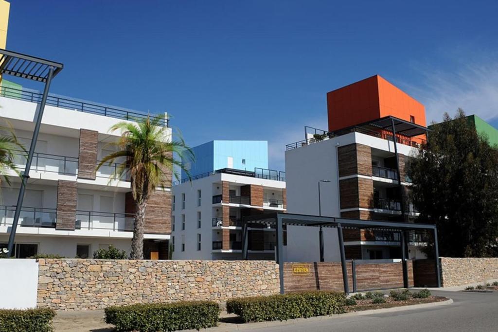 un bâtiment avec un palmier devant dans l'établissement Location saisonnière Résidence Ephyra Gruissan, à Gruissan