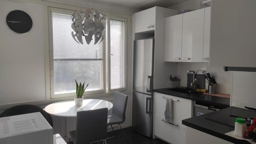 uma cozinha branca com uma mesa e uma janela em Central Park Home em Turku
