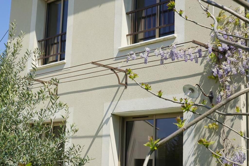 un bâtiment avec des fenêtres et un arbre avec des fleurs violettes dans l'établissement Maison de location 4 personnes, à Saumane-de-Vaucluse