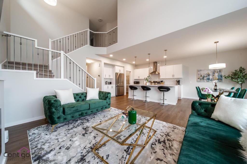 a living room with green couches and a kitchen at Orchards Retreat, AC, Family Friendly, Sleeps 10, NearAirprt in Nisku