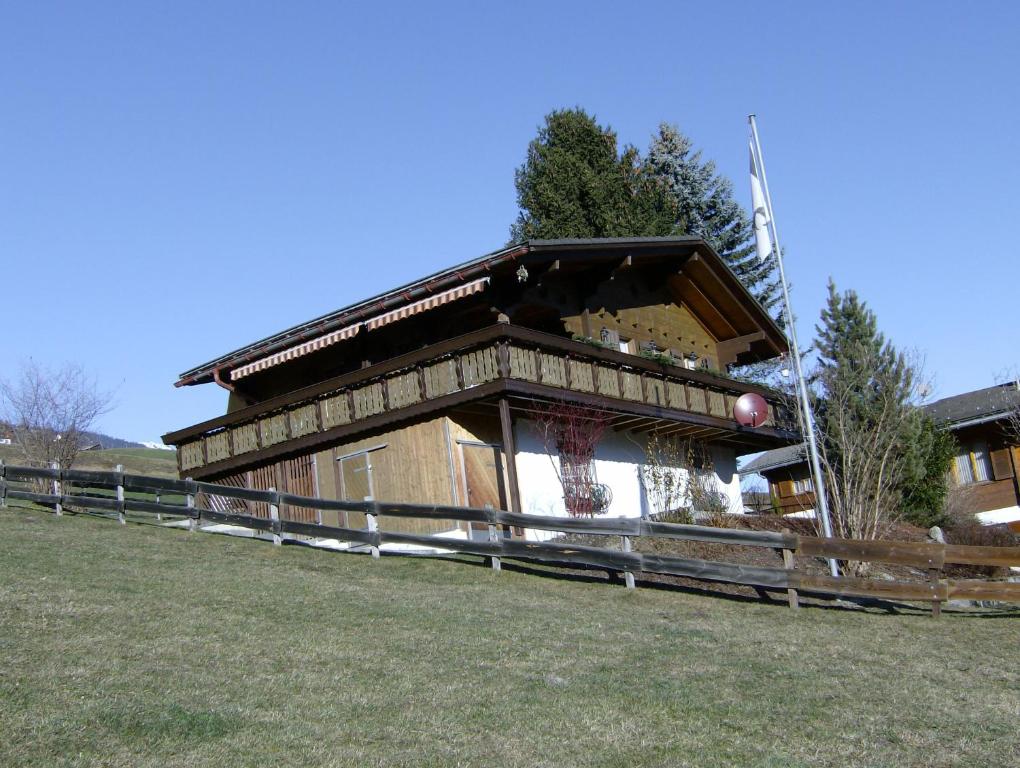 a building with a fence in front of a field at Haus Chalet Beverin in Cazis