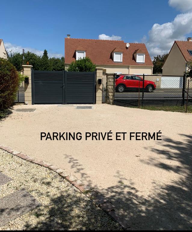 a driveway with a fence and a red car in a house at L&#39;echappée briarde in Marles-en-Brie