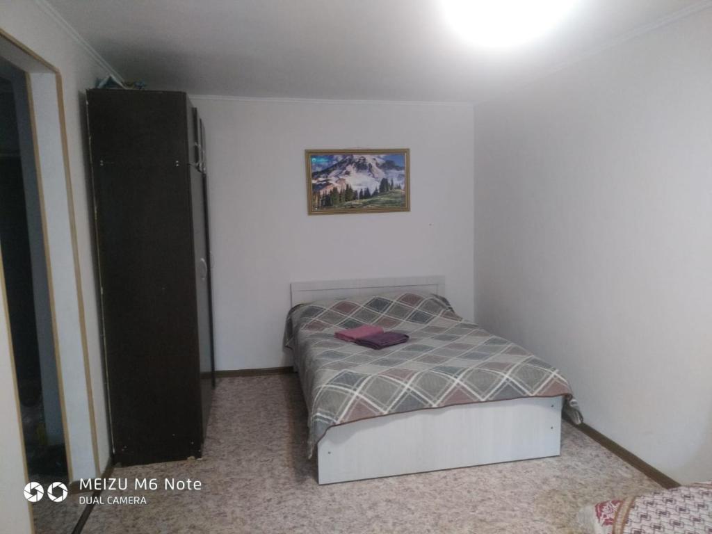 1 dormitorio pequeño con 1 cama y una foto en la pared en 1 комнатные апартаменты в районе Атакента, en Almaty