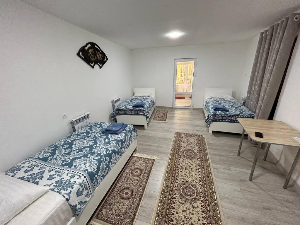 a room with three beds and a table and a table at "Lime" Aparthotel in Bukhara