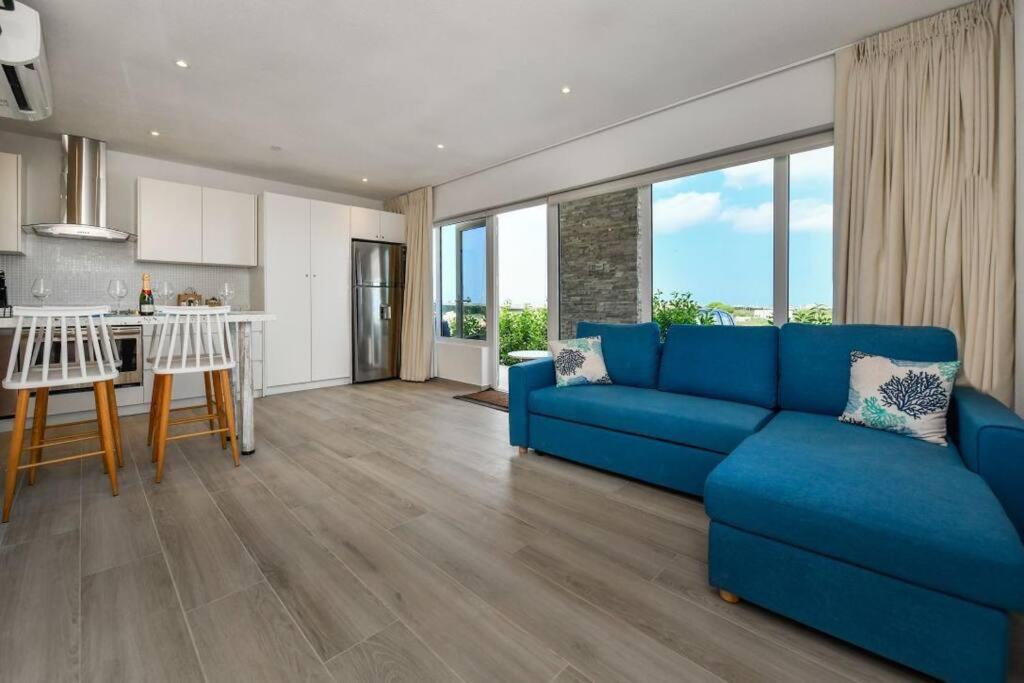 sala de estar con sofá azul y cocina en Commandeurs Apartments unit 4D, en Oranjestad