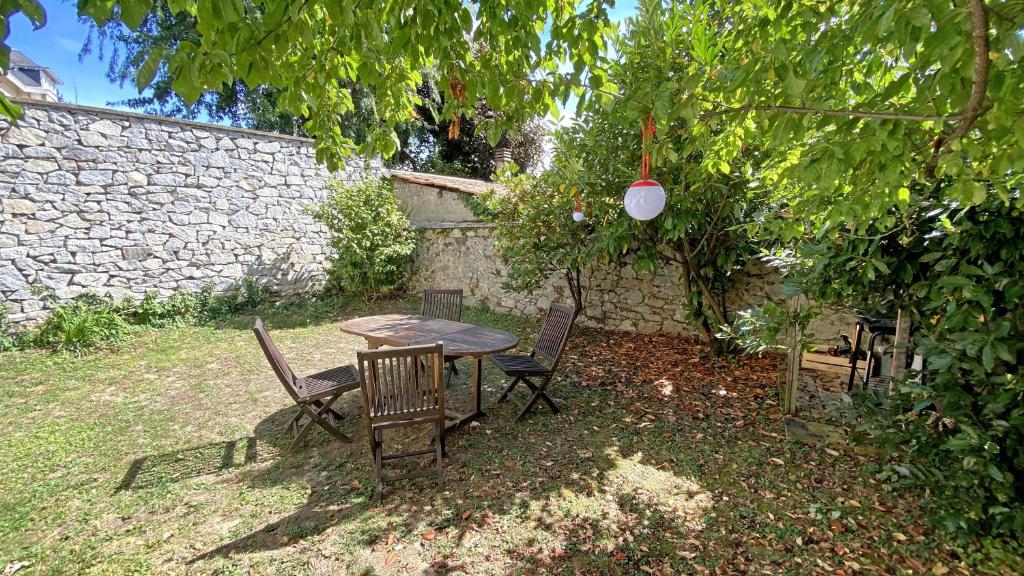 una mesa y sillas en un patio con una pared de piedra en La maison Janisse en Limoges