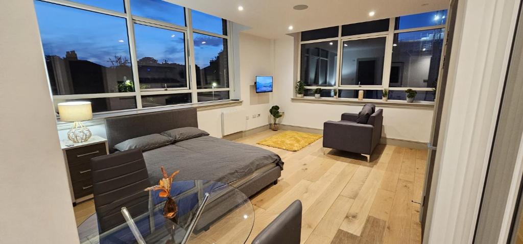 a bedroom with a bed and a chair and windows at Studio flat in Tottenham in London