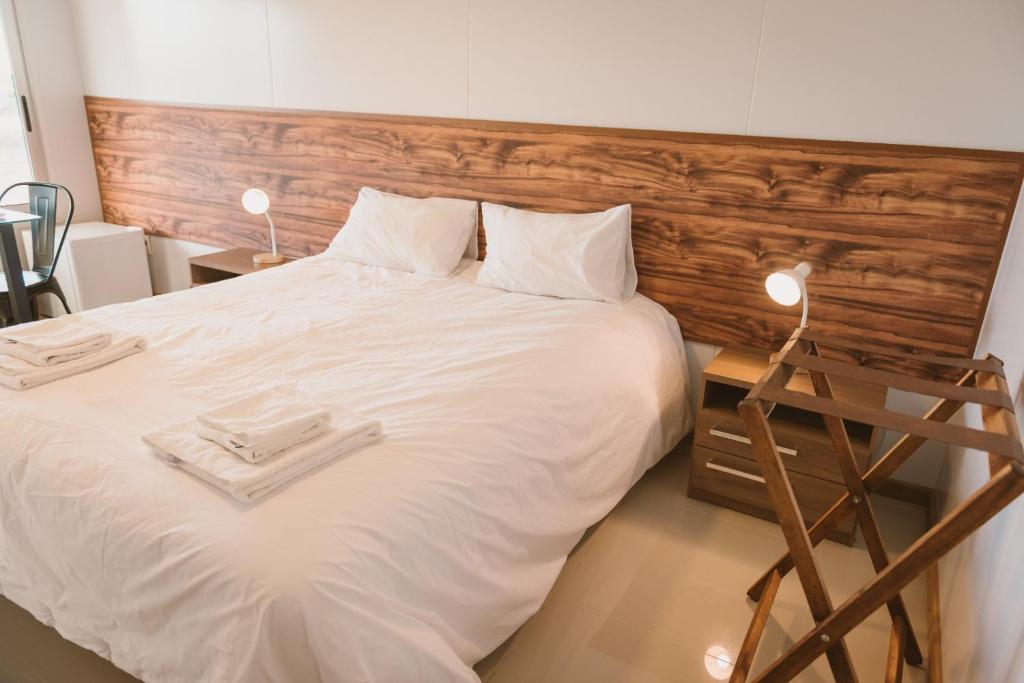 a bedroom with a large white bed with a wooden headboard at HOTEL CONCHILLAS in Conchillas