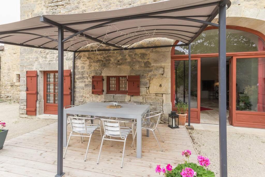 un patio avec une table et des chaises sous un toit dans l'établissement Gite Le Millepertuis - Proche Site Alésia, à Darcey