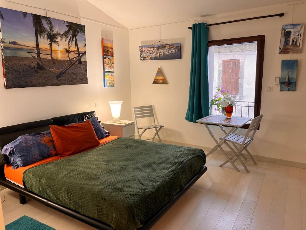 a bedroom with a bed and a table and a window at Chambre cozy spacieuse, intra-muros, clim, parking in Aigues-Mortes