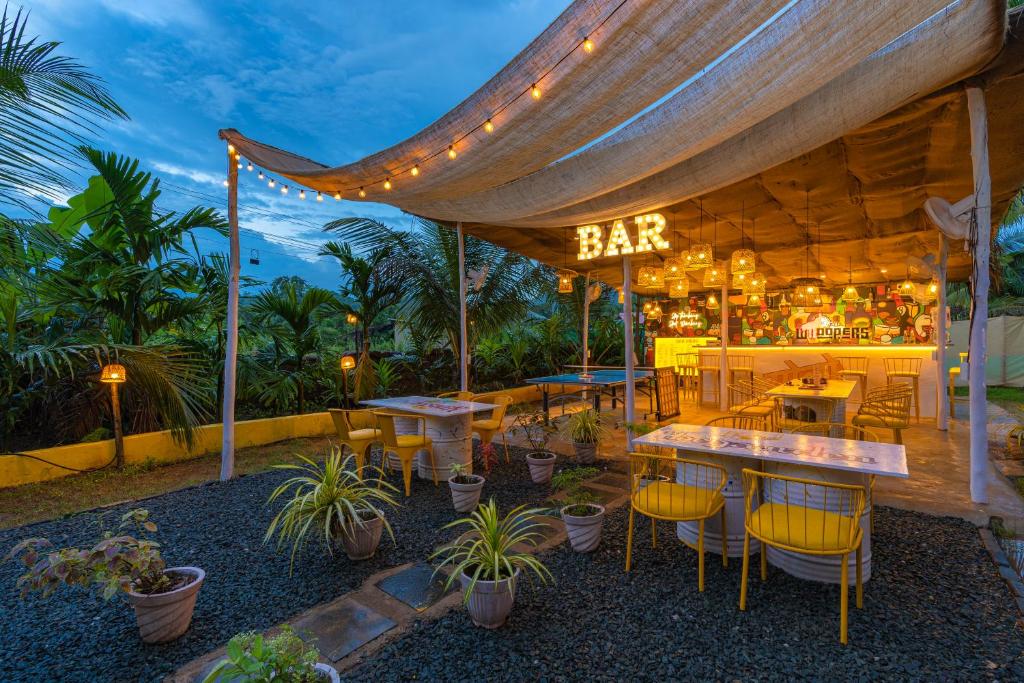 a bar with tables and chairs under a tent at Whoopers Party Hostel, Palolem in Canacona