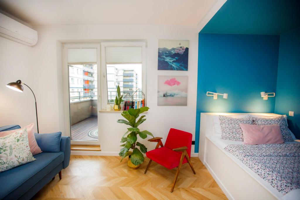 a small room with a bed and a red chair at Bochenka Apartments in Kraków