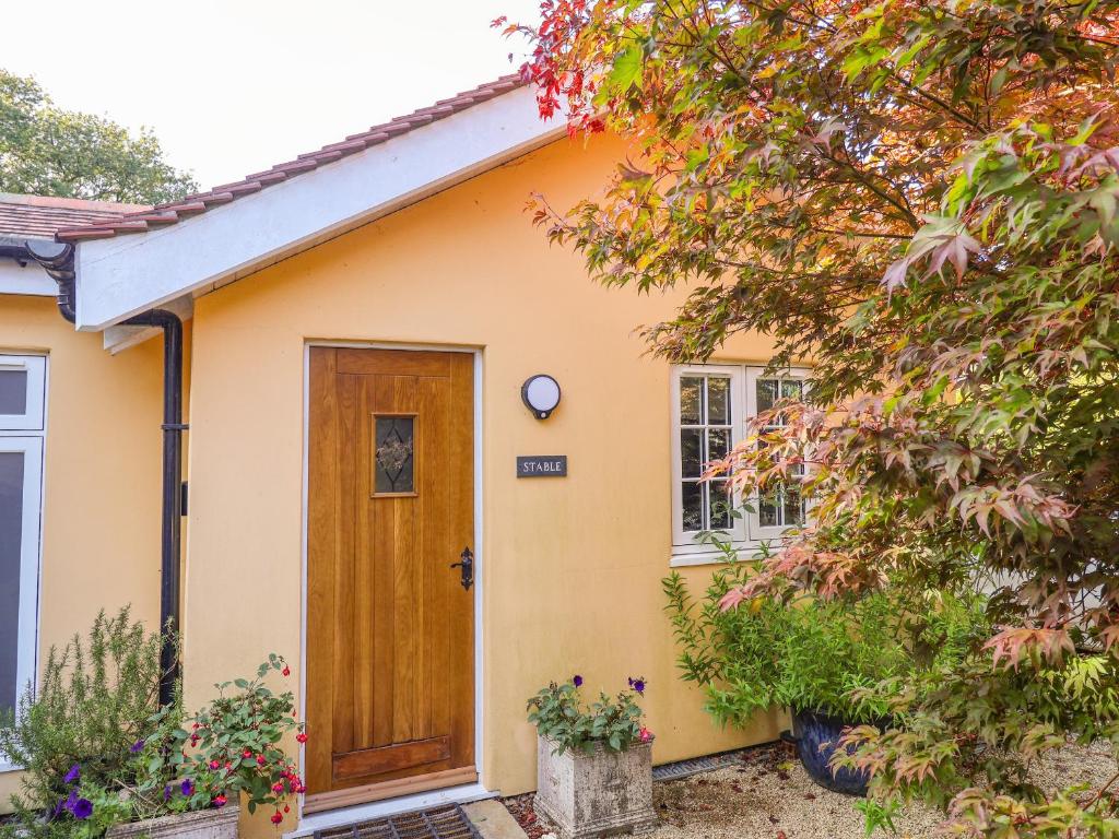 mały żółty dom z drewnianymi drzwiami w obiekcie The Stable w mieście Lyme Regis
