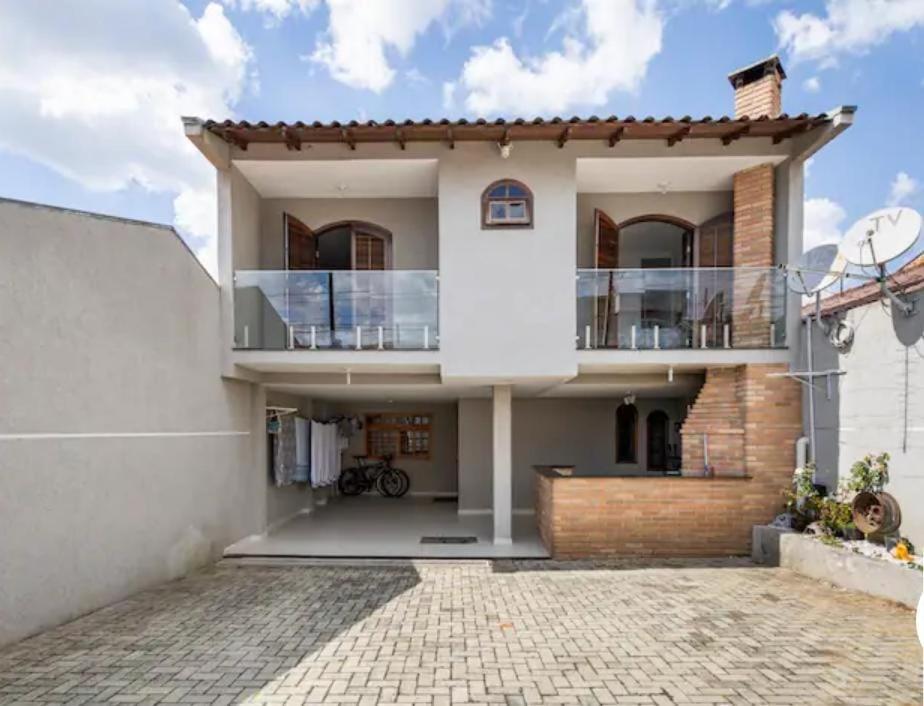 a large white house with a balcony at Quarto em Casa da Família Anton in São José dos Pinhais