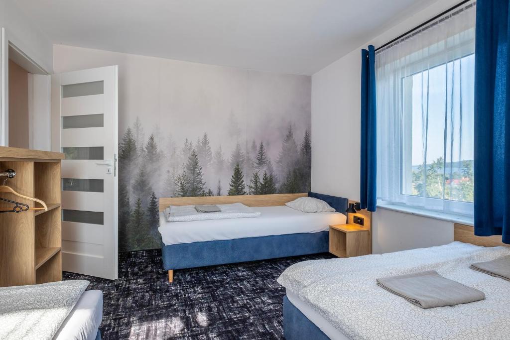 a bedroom with two beds and a mural of trees at 4 Pory Roku Apartamenty Domki Pokoje in Nadole