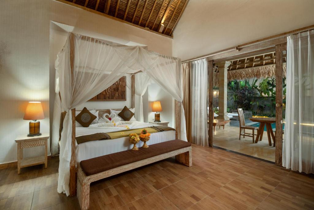 a bedroom with a canopy bed and a patio at The Kanjeng resort Ubud in Ubud