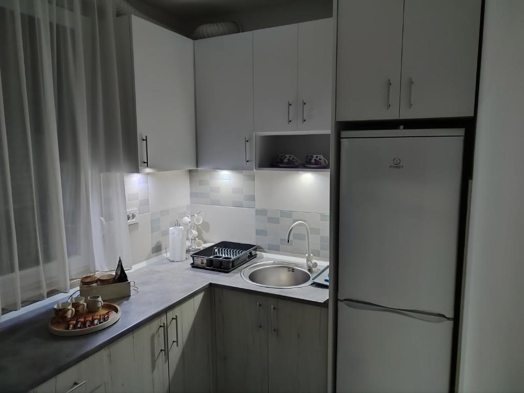 a kitchen with white cabinets and a sink and a refrigerator at Apartman LUXNS Novi Sad in Pasuljište