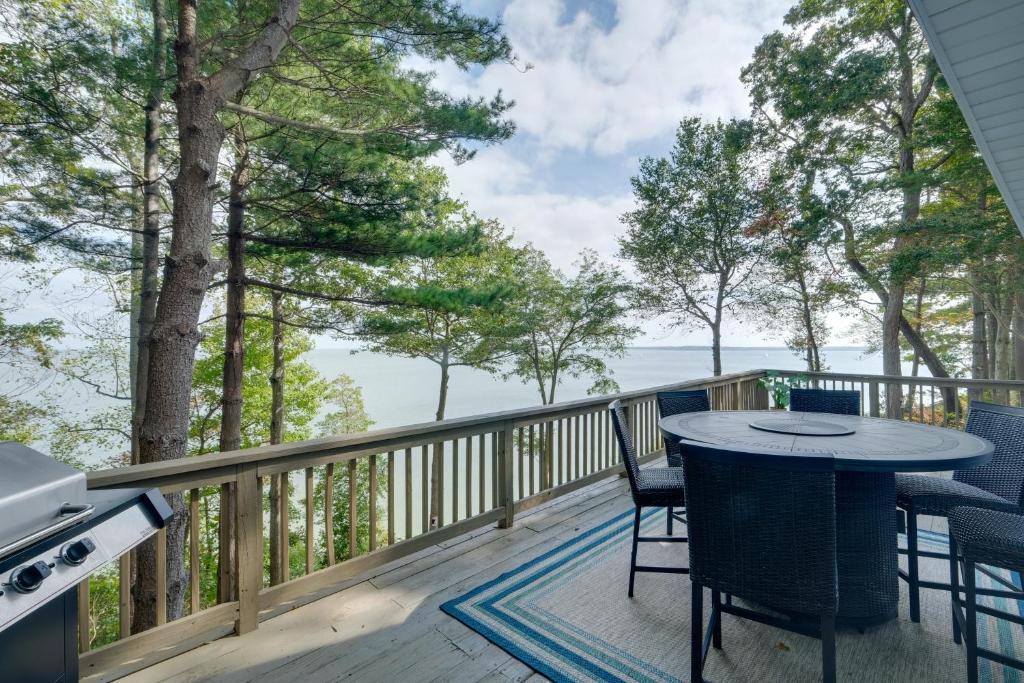 eine Terrasse mit einem Tisch, Stühlen und einem Grill in der Unterkunft Waterfront Lusby Home with Deck and Stunning Views! in Lusby