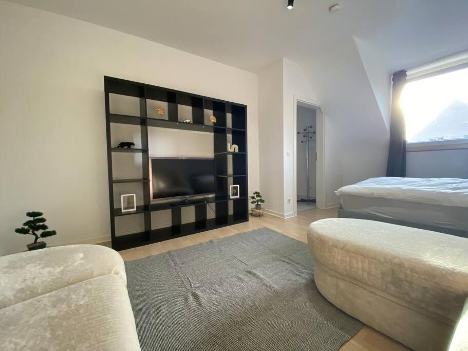ein Wohnzimmer mit einem TV, einem Bett und einem Sofa in der Unterkunft Ruhiges DG - 6 P. - urban - ÖPNV in Köln