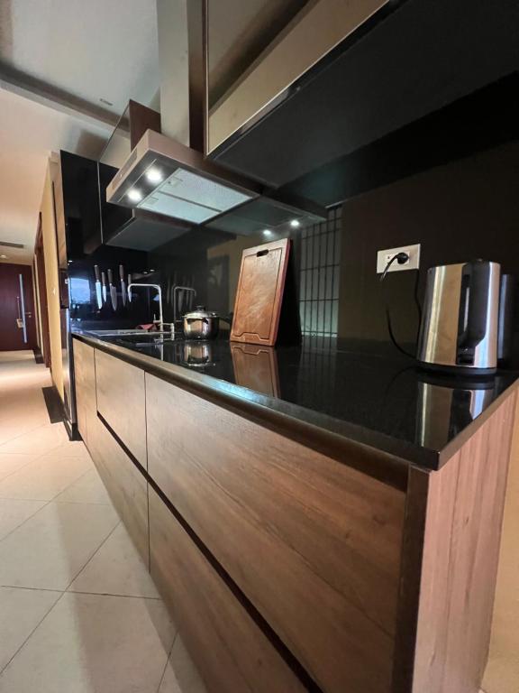a kitchen with a black counter top and wooden cabinets at Luxury Apartment Kata Beach The Accenta in Kata Beach