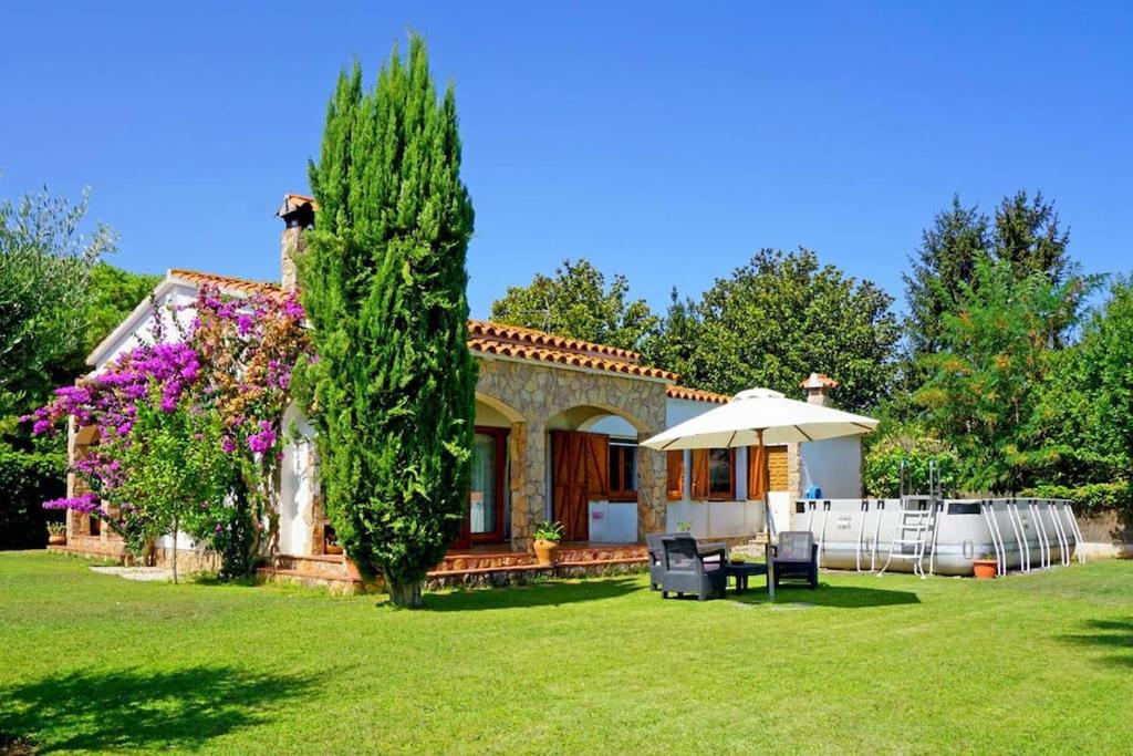 a house with an umbrella and a yard at Casa en Viladamat con piscina en la Costa Brava in Viladamat