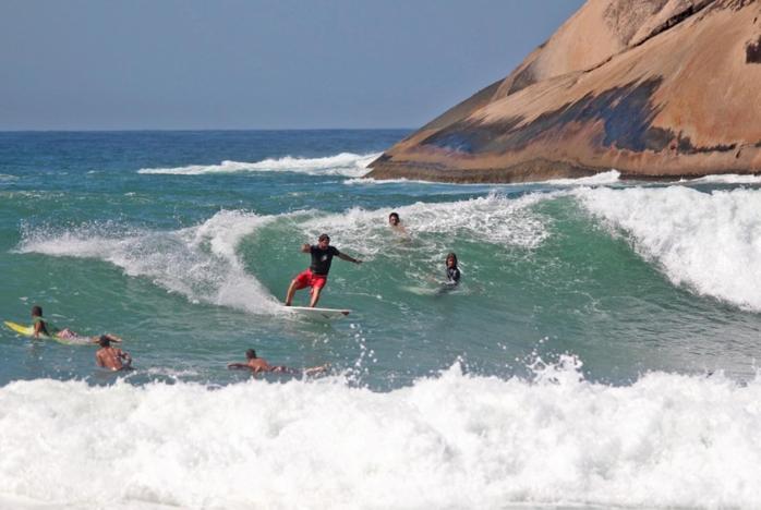 un grupo de personas montando una ola en tablas de surf en el océano en brisa praiana, en Río de Janeiro
