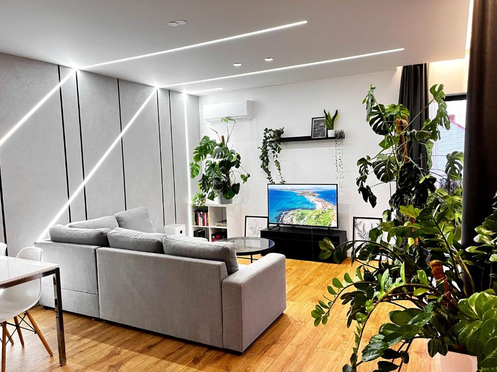 una sala de estar con sofá y muchas plantas en Apartament Green Plant - 2 oddzielne sypialnie, taras 30m2 i garaż podziemny, en Kielce