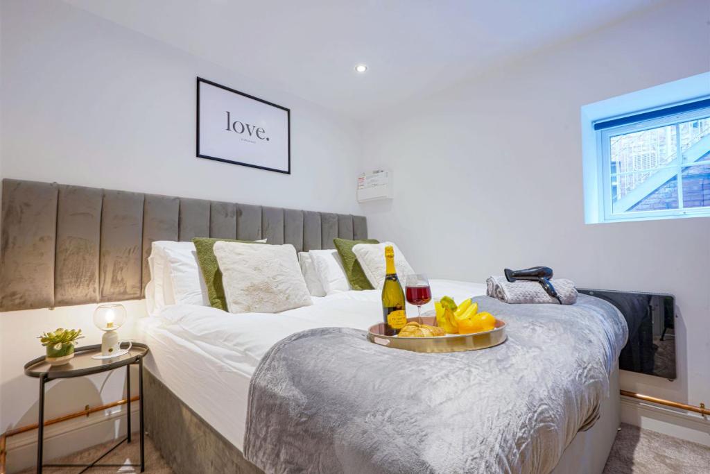 a bed with a tray of fruit and a bottle of wine at Boutique Apartment - City Centre - Free Parking, Fast Wifi and Smart TV by Yoko Property in Rugby