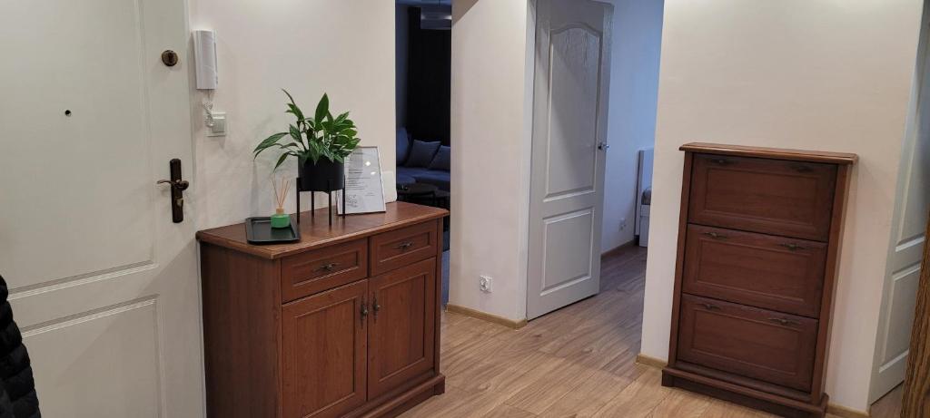 a room with a wooden dresser with a plant on it at Incanto Apartament in Starogard Gdański
