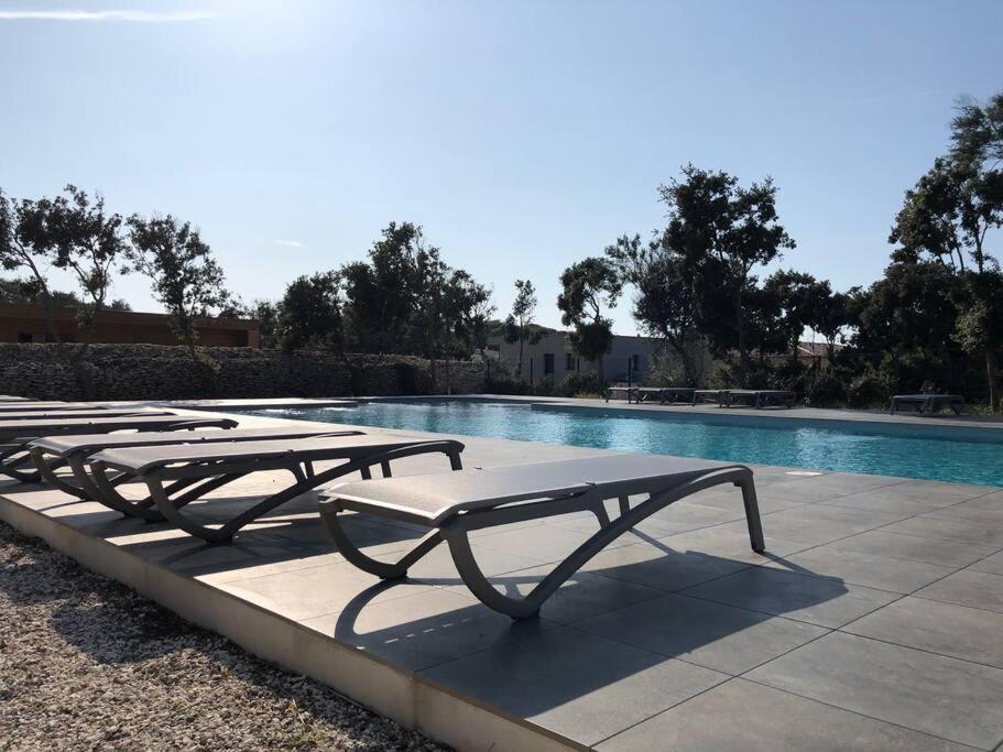 - une rangée de tables de pique-nique à côté de la piscine dans l'établissement Villa Noelly - Résidence les Hauts de Bonifacio, à Bonifacio