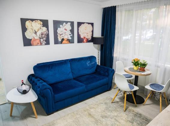 a blue couch in a living room with tables and chairs at Escape Aparthotel in Suceava