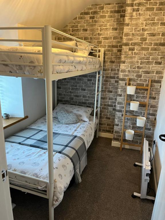 a bedroom with two bunk beds and a brick wall at Cosy 2 bedroom cottage in Llanuwchllyn