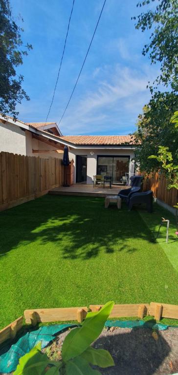 une cour avec une pelouse verdoyante dans l'établissement Le petit Paradis,, proche plage du Mauret - Bassin, à Andernos-les-Bains
