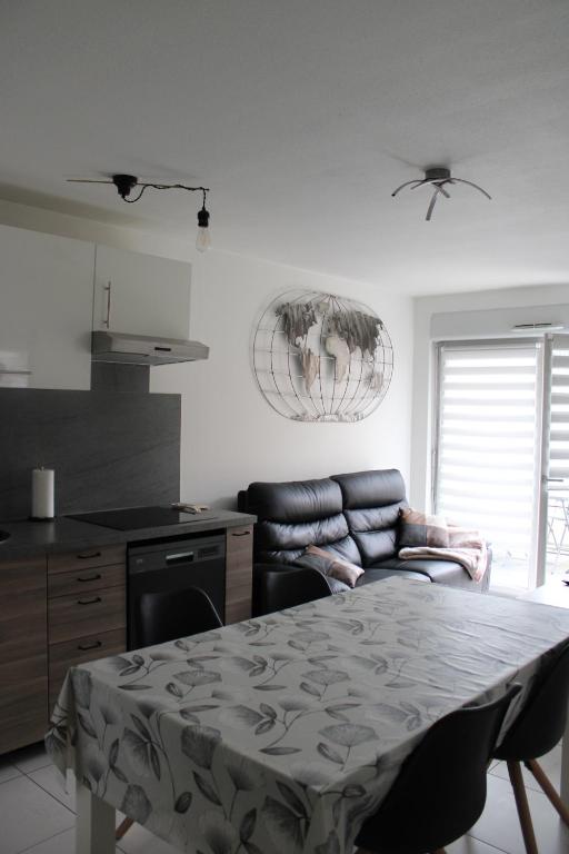 a kitchen with a table and a couch in a room at Appartement confortable avec parking privé in Schiltigheim