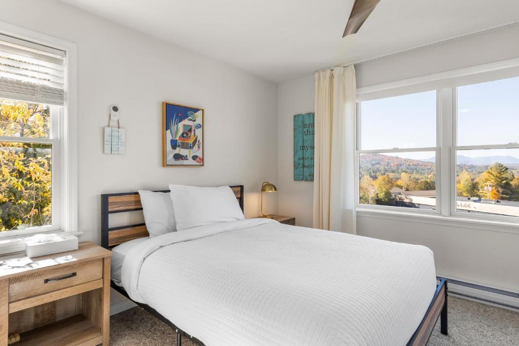a white bedroom with a bed and two windows at Amazing Mountain Views Lake Placid & 1980 Olympic Center in Lake Placid