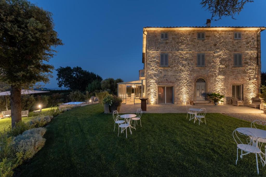 an estate with tables and chairs in front of a building at Relais Maria Cristina in Chianni