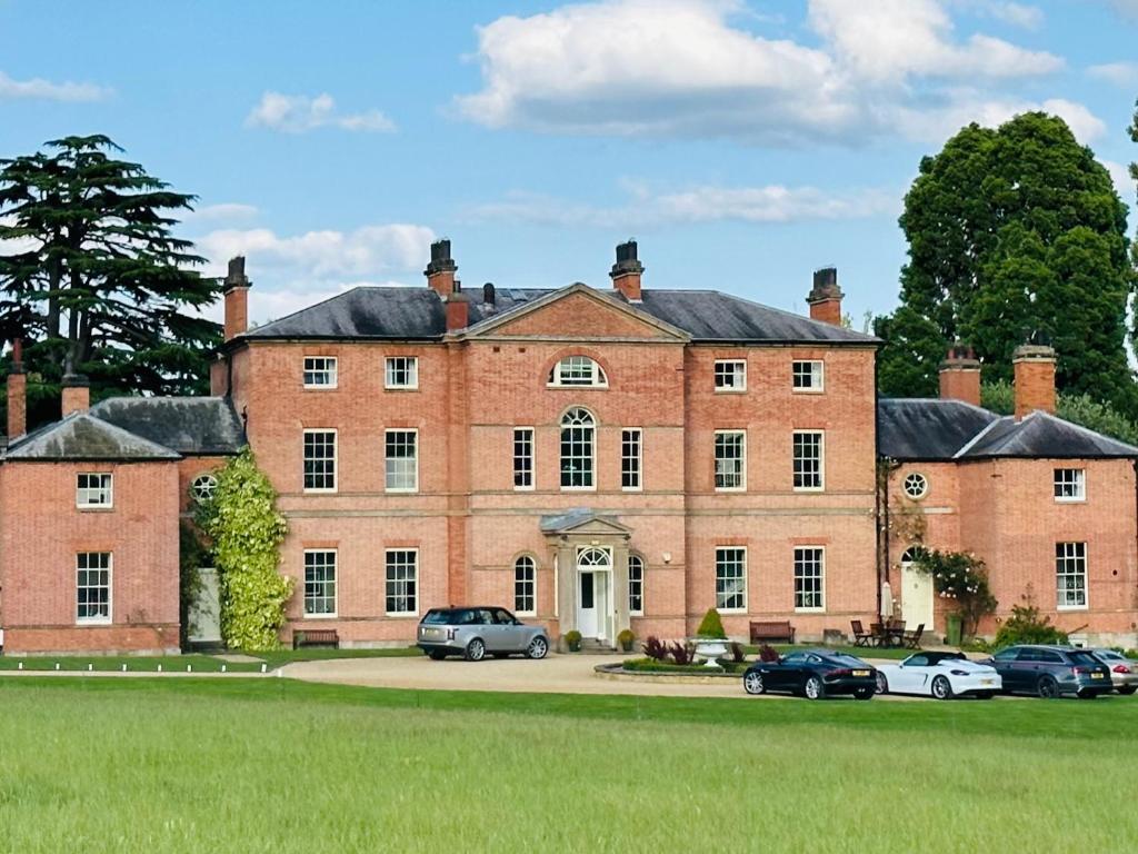 a large brick building with cars parked in front of it at Stunning Countryside Home with Hot Tub - Sleeps 8 in Thurgarton