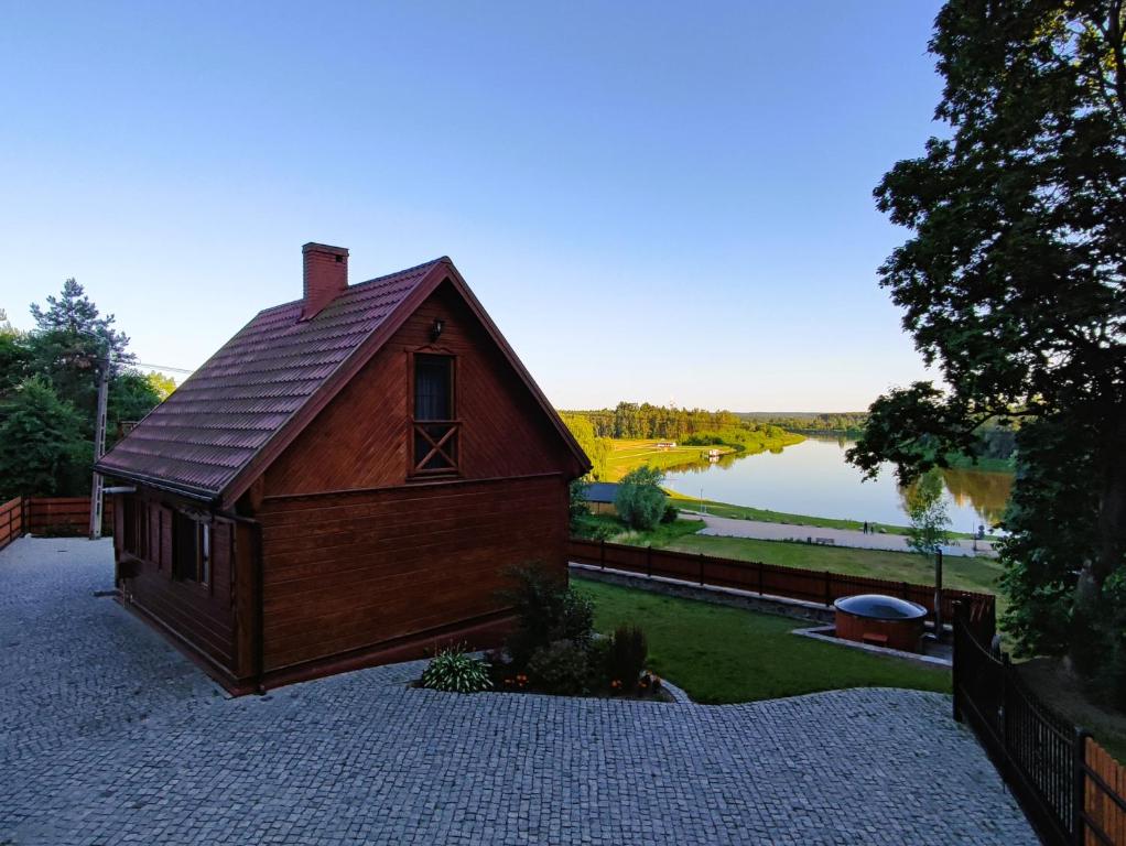 una pequeña casa de madera con un lago en el fondo en Bug Na Skarpie - Domek Wypoczynkowy z Jacuzzi i Kominkiem en Drohiczyn nad Bugiem