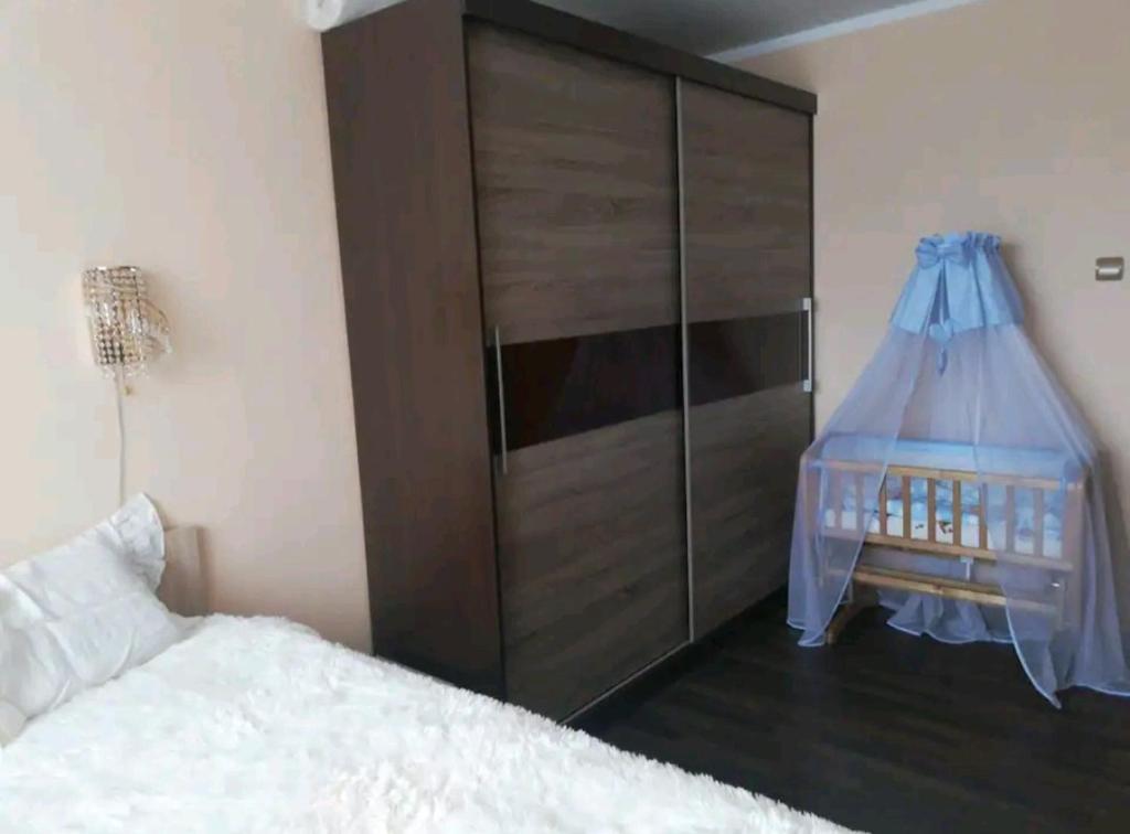 a bedroom with a large cabinet with a baby crib at Baby friendly 1-bedroom rental w/ free parking in Sigulda