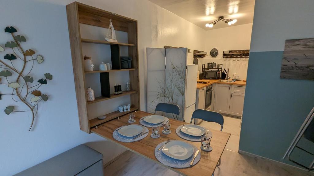 una cocina con una mesa de madera con platos. en Wald und Meer, en Glücksburg