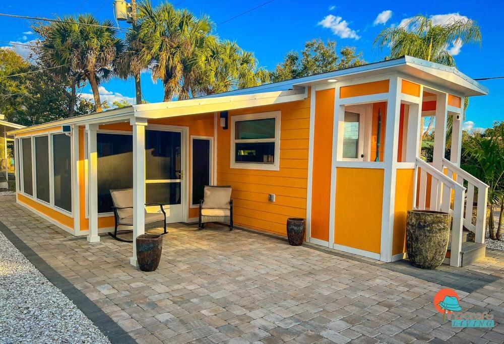 mały pomarańczowy dom z telewizorem na patio w obiekcie Pinecraft Sunset Tiny Home w mieście Sarasota