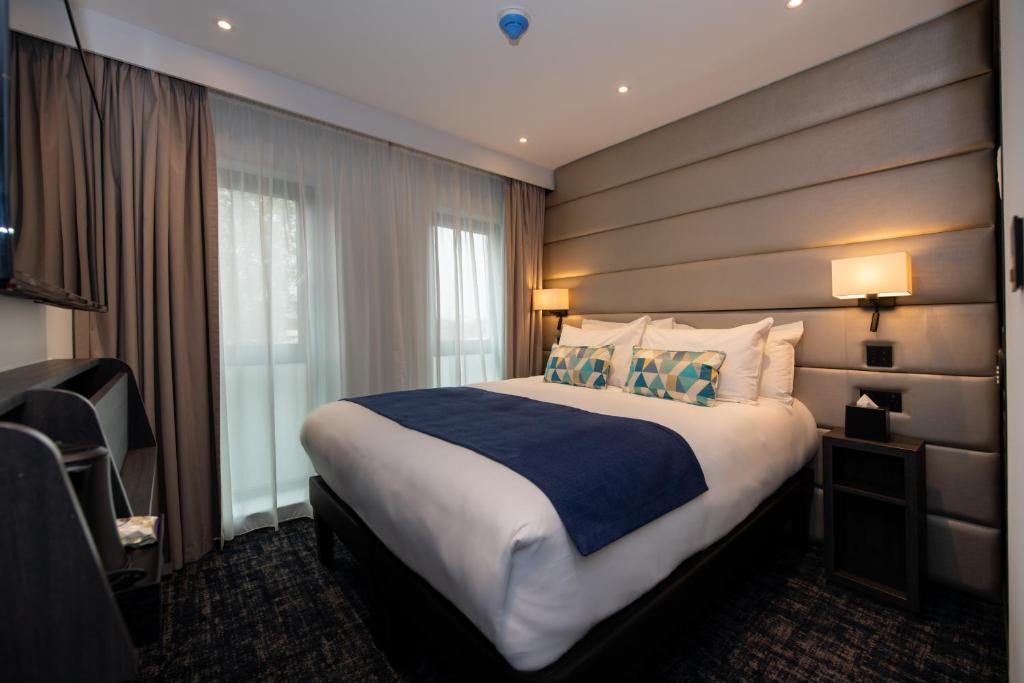 um quarto de hotel com uma cama grande e uma janela em Signature London, The J Marylebone em Londres